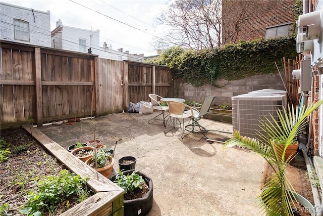 view of patio with a garden, outdoor dining area, central AC, and a fenced backyard