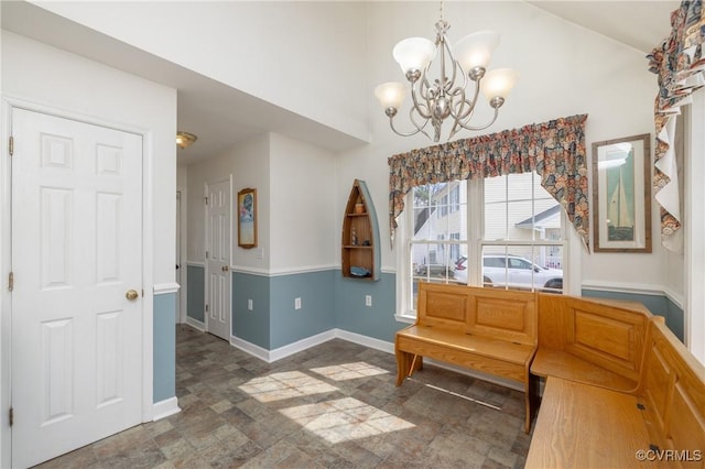 interior space featuring a chandelier, stone finish flooring, baseboards, and a towering ceiling