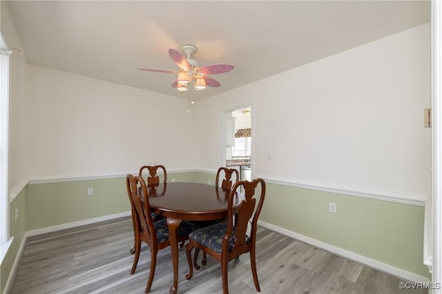 dining space with baseboards, ceiling fan, and light wood finished floors