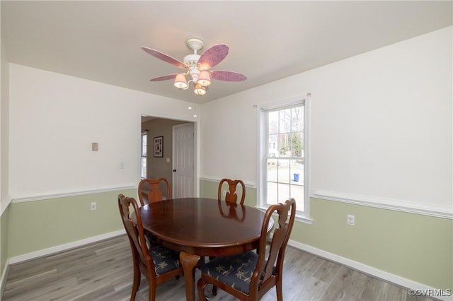 dining space with a ceiling fan, baseboards, and light wood-type flooring