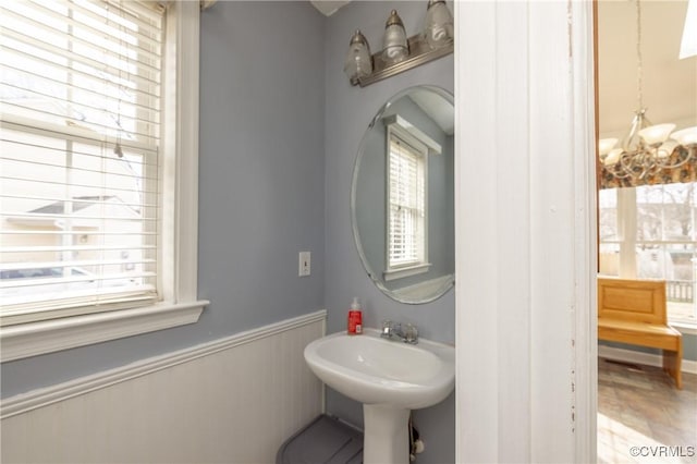 bathroom featuring a sink, a wainscoted wall, and a chandelier