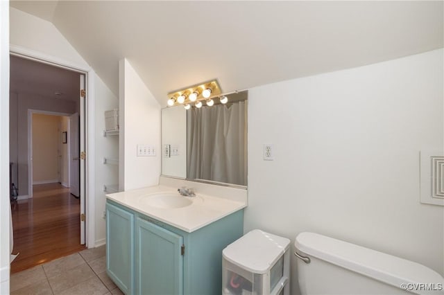 bathroom featuring tile patterned floors, lofted ceiling, toilet, and vanity