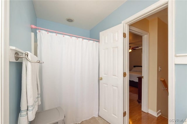 full bath with a shower with curtain and wood finished floors