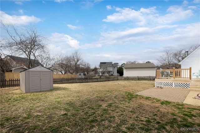 view of yard with a wooden deck, an outdoor structure, a fenced backyard, and a shed