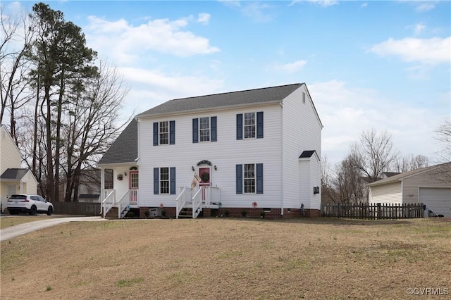 colonial inspired home featuring crawl space, a shingled roof, a front yard, and fence