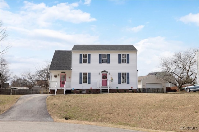 colonial-style house featuring crawl space, a front yard, a garage, and fence