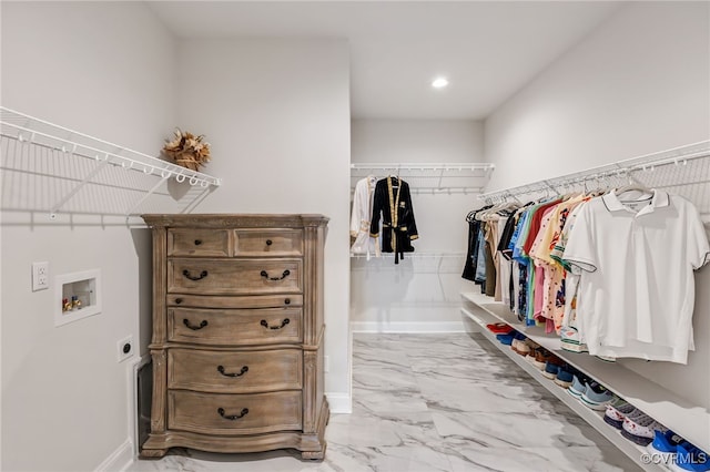 walk in closet featuring marble finish flooring