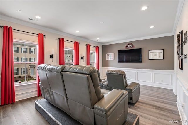 home theater room featuring crown molding, recessed lighting, a wainscoted wall, and wood finished floors