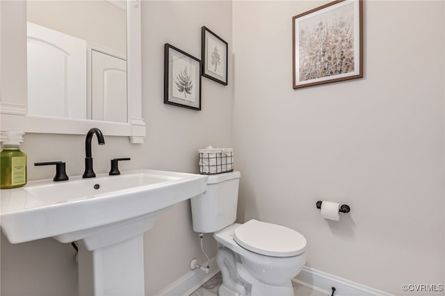 bathroom with baseboards, toilet, and a sink