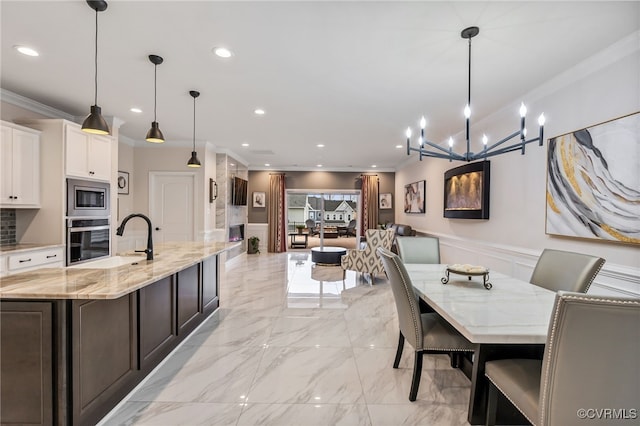 dining room with ornamental molding, a wainscoted wall, recessed lighting, light marble finish flooring, and a chandelier