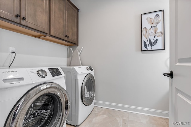 laundry room featuring baseboards, cabinet space, and washer and clothes dryer