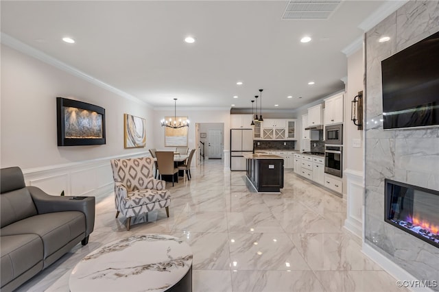 living room with ornamental molding, a chandelier, light marble finish floors, recessed lighting, and a wainscoted wall
