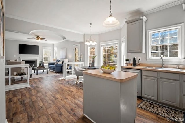 kitchen with gray cabinets, a sink, stainless steel dishwasher, a center island, and arched walkways