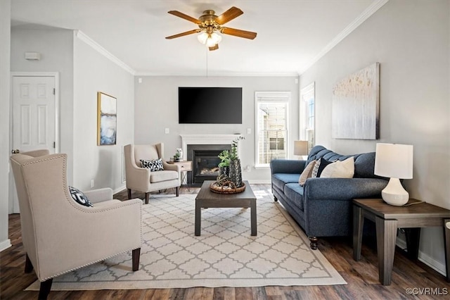 living area with crown molding, wood finished floors, baseboards, and ceiling fan