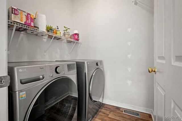 washroom featuring visible vents, washer and clothes dryer, wood finished floors, baseboards, and laundry area