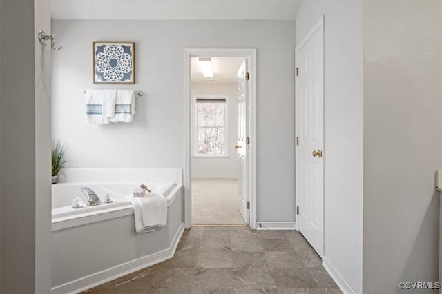 bathroom with baseboards and a bath