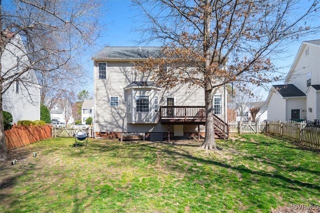 rear view of property featuring a deck, a lawn, and a fenced backyard