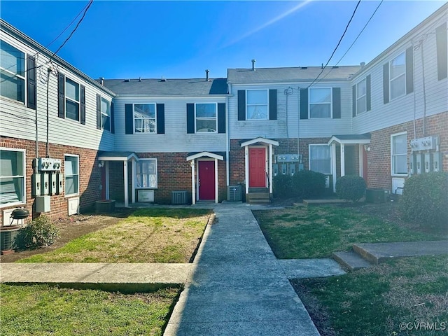 multi unit property with brick siding, cooling unit, and a front yard