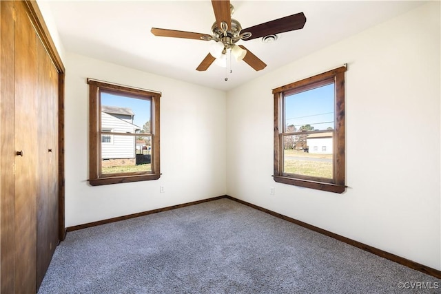 carpeted empty room with baseboards, a wealth of natural light, and ceiling fan