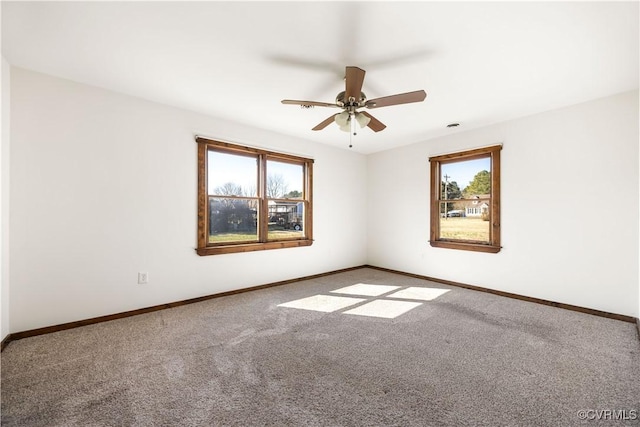 carpeted spare room with a ceiling fan, a healthy amount of sunlight, and baseboards