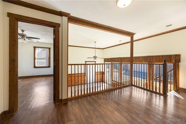 corridor with a healthy amount of sunlight, wood finished floors, baseboards, and ornamental molding