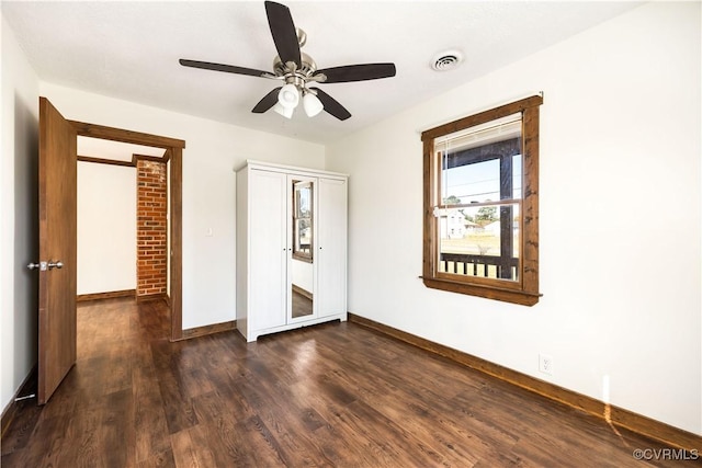 unfurnished bedroom with dark wood-style floors, visible vents, ceiling fan, and baseboards