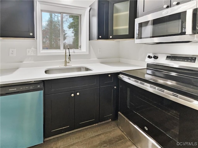 kitchen featuring dark cabinetry, light countertops, appliances with stainless steel finishes, and a sink