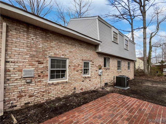 exterior space featuring a patio, cooling unit, brick siding, and crawl space