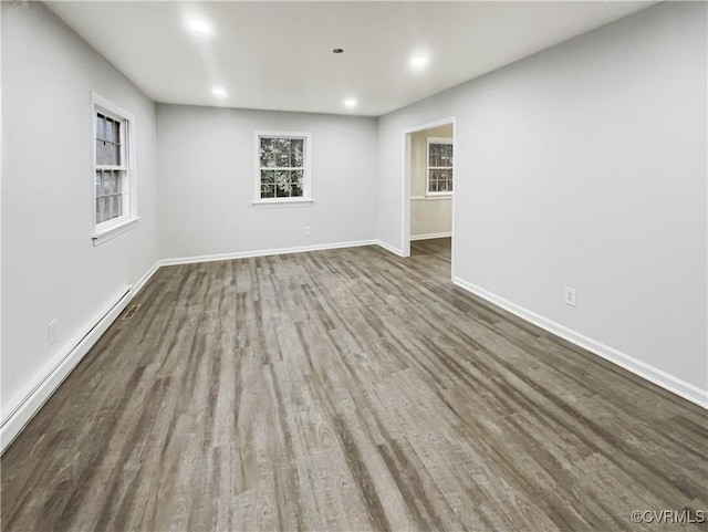 spare room featuring recessed lighting, wood finished floors, baseboards, and a baseboard radiator