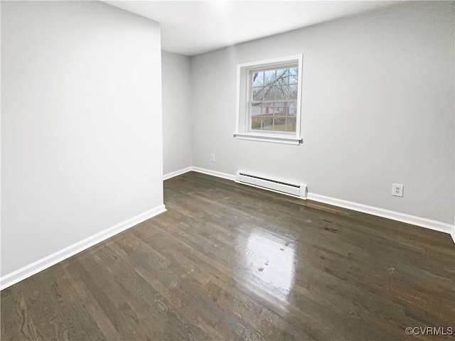 unfurnished room featuring a baseboard heating unit, baseboards, and wood finished floors