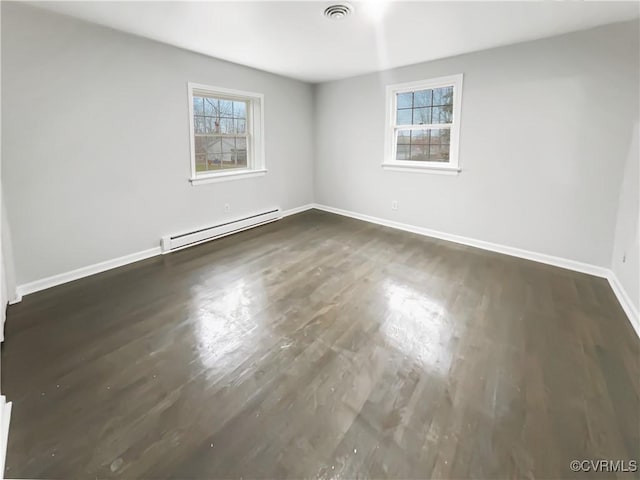 unfurnished room featuring wood finished floors, visible vents, baseboards, and a baseboard radiator