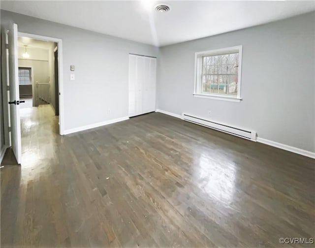 unfurnished bedroom featuring baseboards, visible vents, dark wood-type flooring, a closet, and baseboard heating