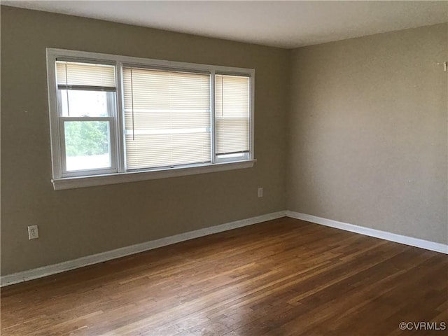 unfurnished room featuring baseboards and dark wood-style floors