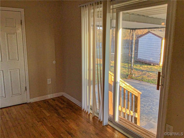 doorway with wood finished floors and baseboards