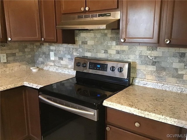 kitchen with under cabinet range hood, electric range, and decorative backsplash