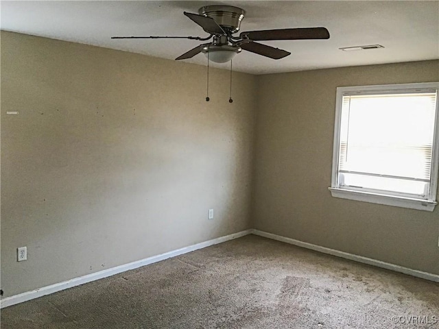 carpeted spare room featuring visible vents, baseboards, and a ceiling fan