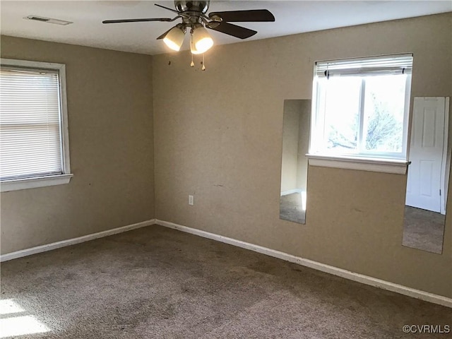 empty room with carpet flooring, baseboards, visible vents, and a wealth of natural light