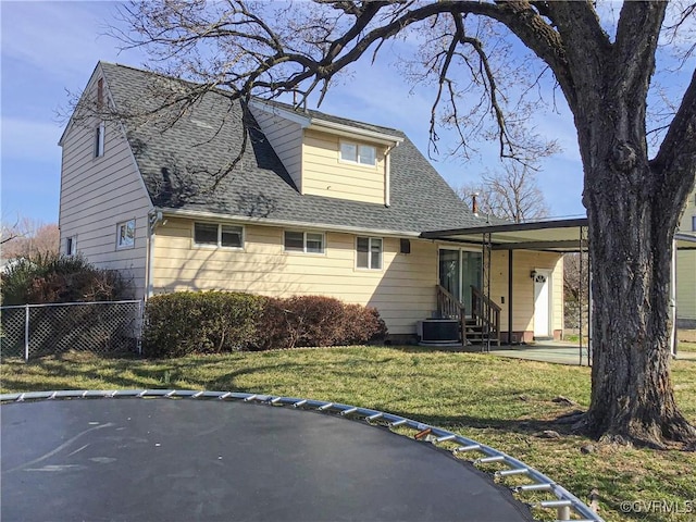 rear view of house featuring a lawn, roof with shingles, and fence