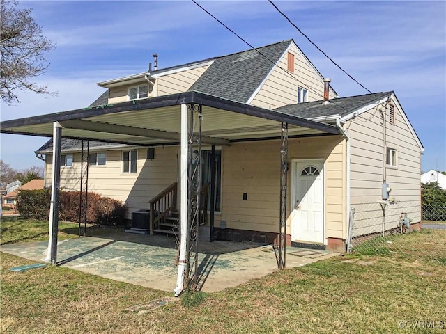 back of property featuring a lawn, entry steps, and a shingled roof