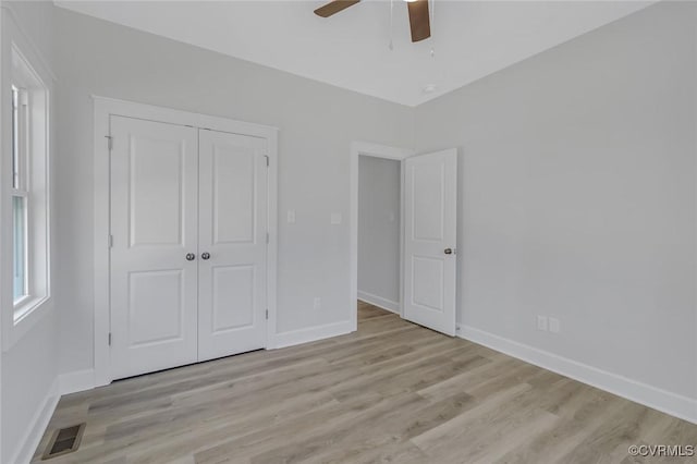 unfurnished bedroom with visible vents, baseboards, light wood-style floors, and a closet