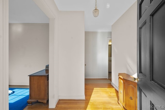 corridor featuring baseboards and light wood finished floors