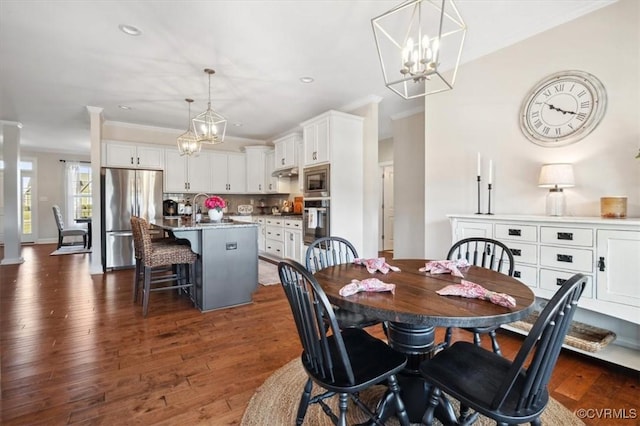 dining area with a notable chandelier, recessed lighting, dark wood-type flooring, and ornamental molding