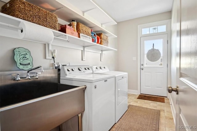 laundry area with laundry area, washing machine and dryer, baseboards, and a sink