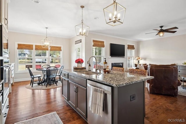 kitchen with a healthy amount of sunlight, dark wood finished floors, a fireplace, stainless steel dishwasher, and crown molding