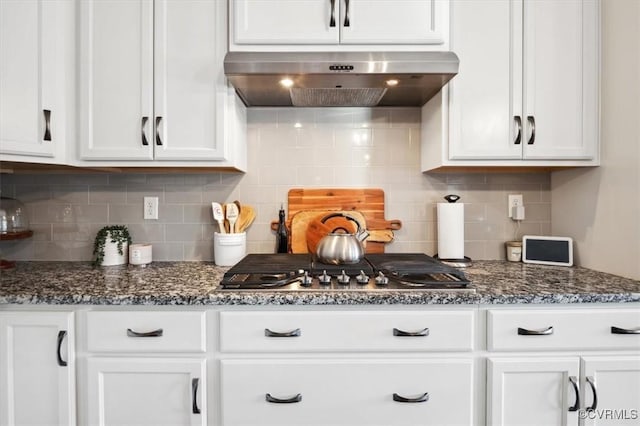 kitchen featuring dark stone countertops, white cabinets, and exhaust hood