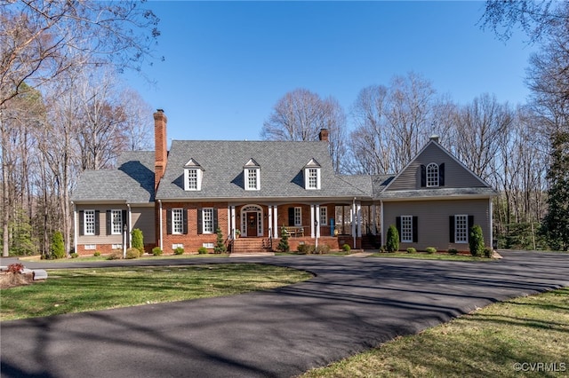 cape cod home with a front yard, brick siding, covered porch, and crawl space