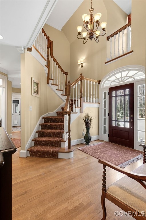 entryway with a notable chandelier, wood finished floors, a high ceiling, baseboards, and stairs