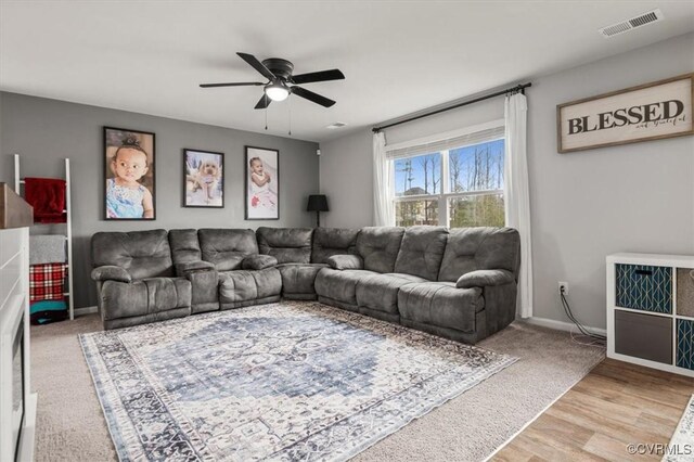 living area featuring visible vents, a ceiling fan, baseboards, and wood finished floors