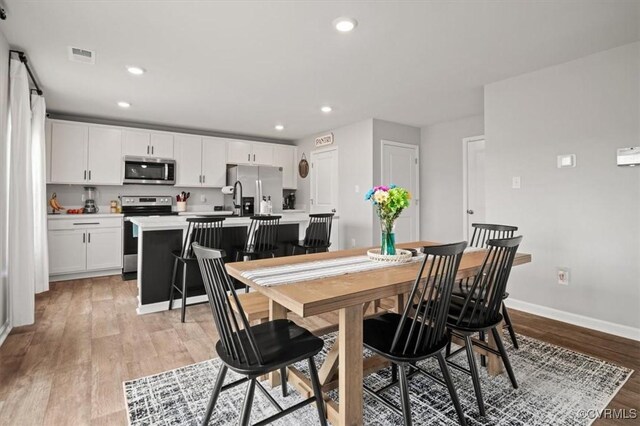 dining area featuring light wood-style flooring, recessed lighting, visible vents, and baseboards