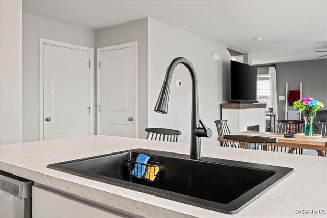 kitchen featuring dishwasher, light countertops, and a sink